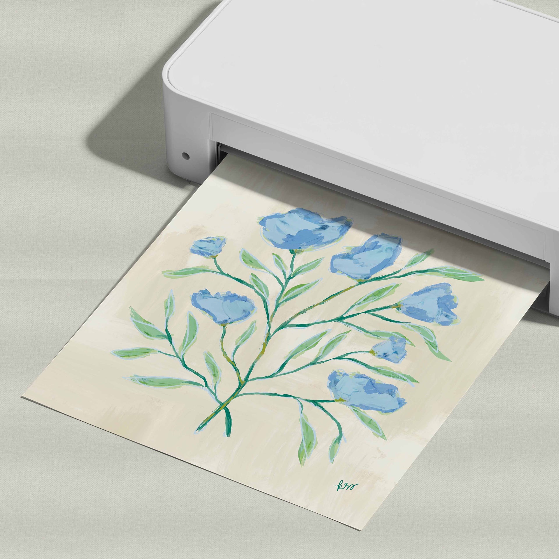A white printer is displaying a printed image of a blue flower arrangement on a light-colored paper.