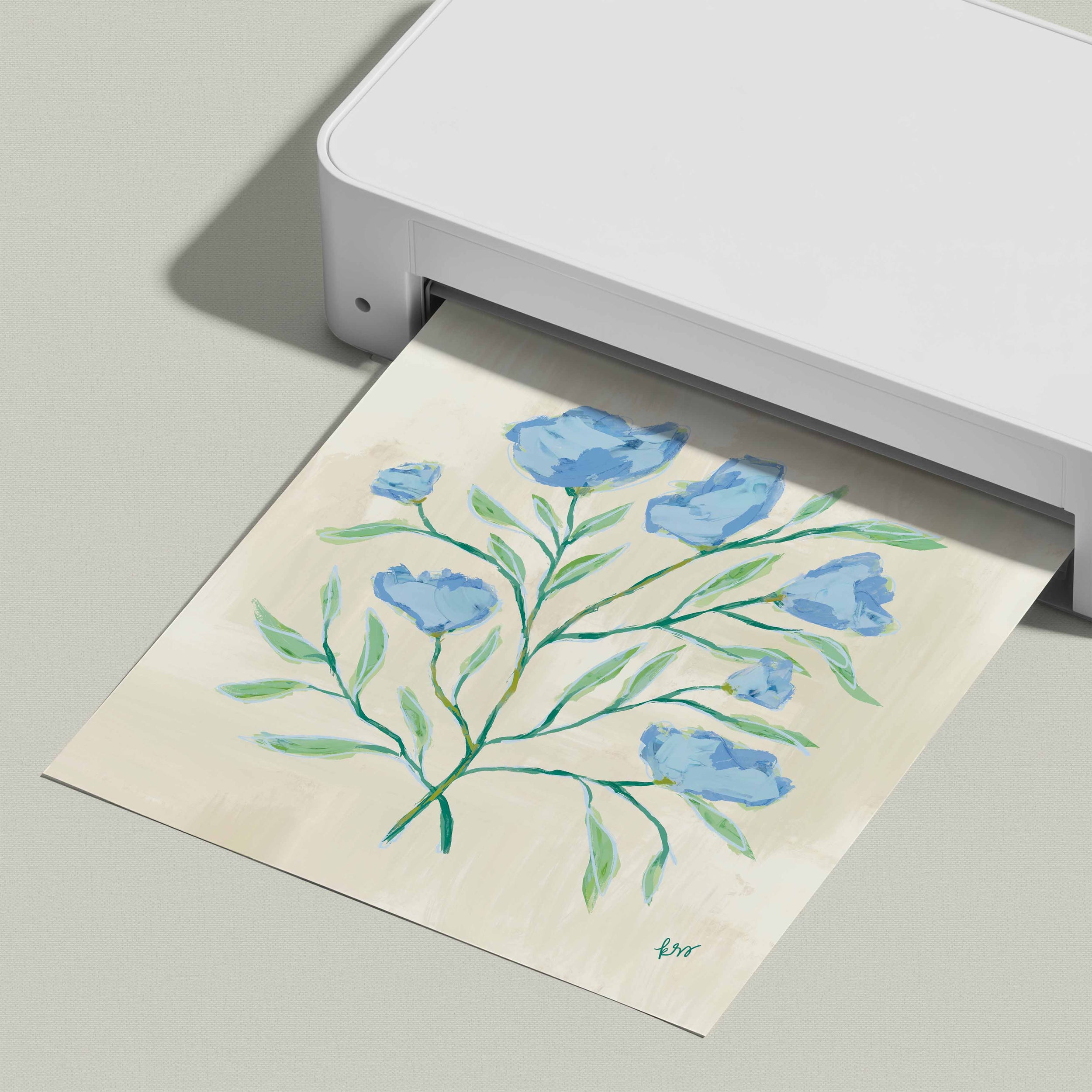 A white printer is displaying a printed image of a blue flower arrangement on a light-colored paper.