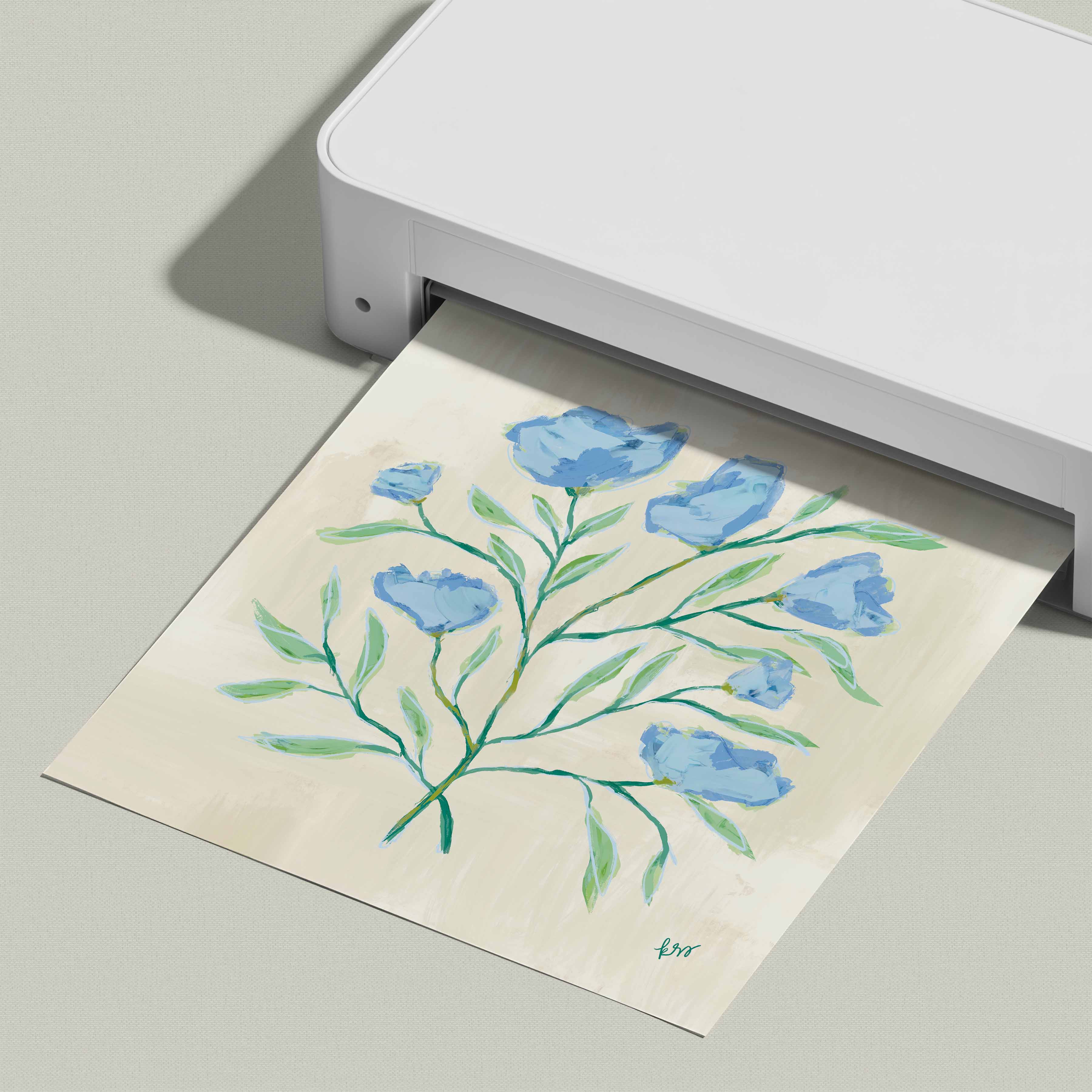 A white printer is displaying a printed image of a blue flower arrangement on a light-colored paper.