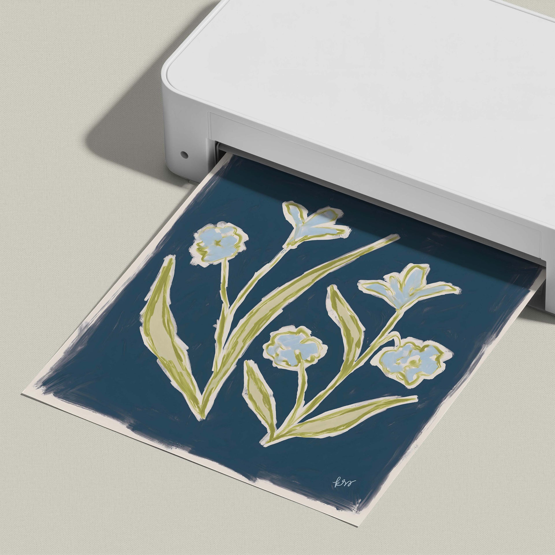 A white printer is displaying a printed image of a blue floral design on a dark background.