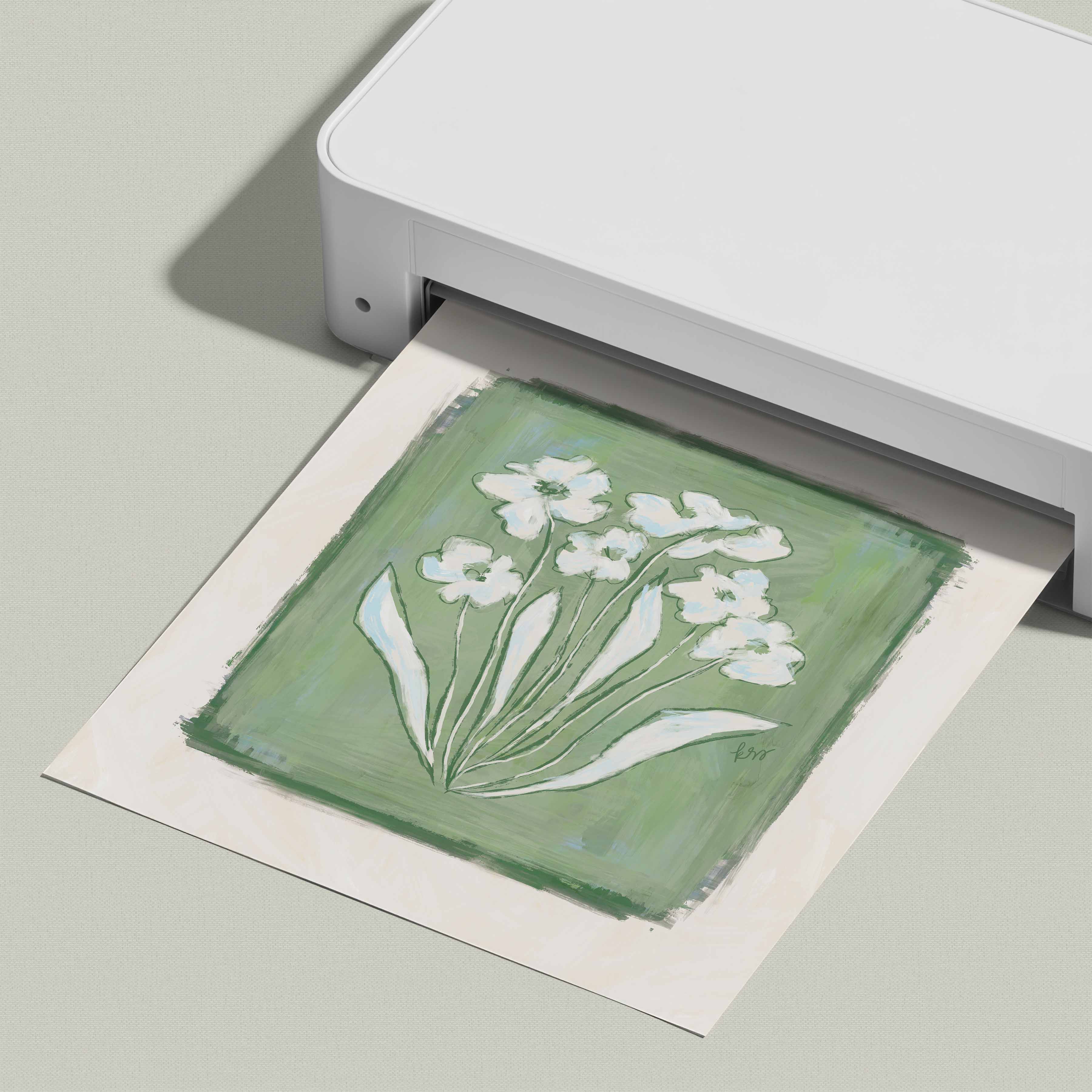 A white printer is printing a square image of white flowers on a green background.