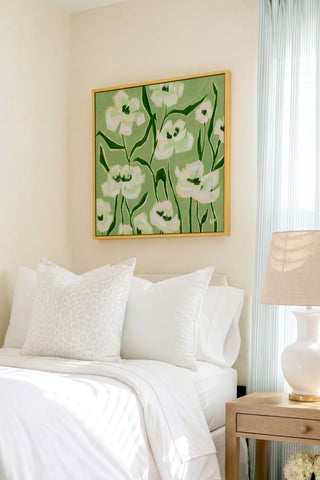 a cozy bedroom with a bed, a nightstand, and a framed floral artwork on the wall.