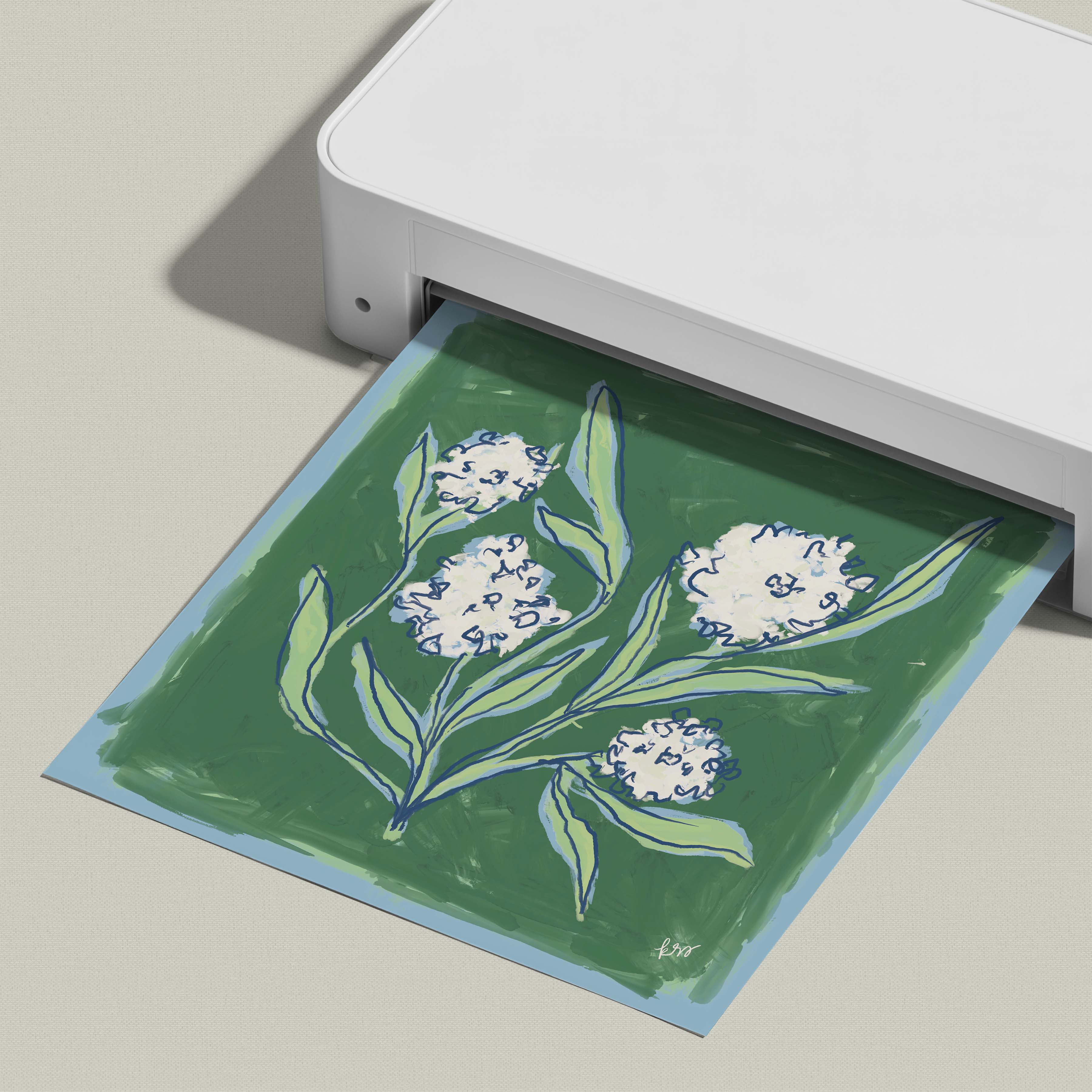A white printer is printing a green and white floral design on a piece of paper.