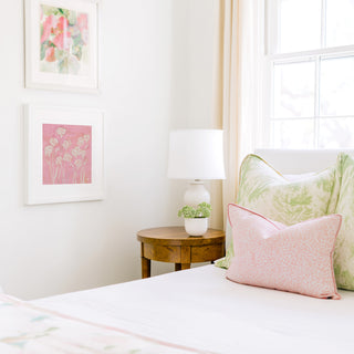 a cozy bedroom corner with a bed, a wooden nightstand, and a framed artwork on the wall.