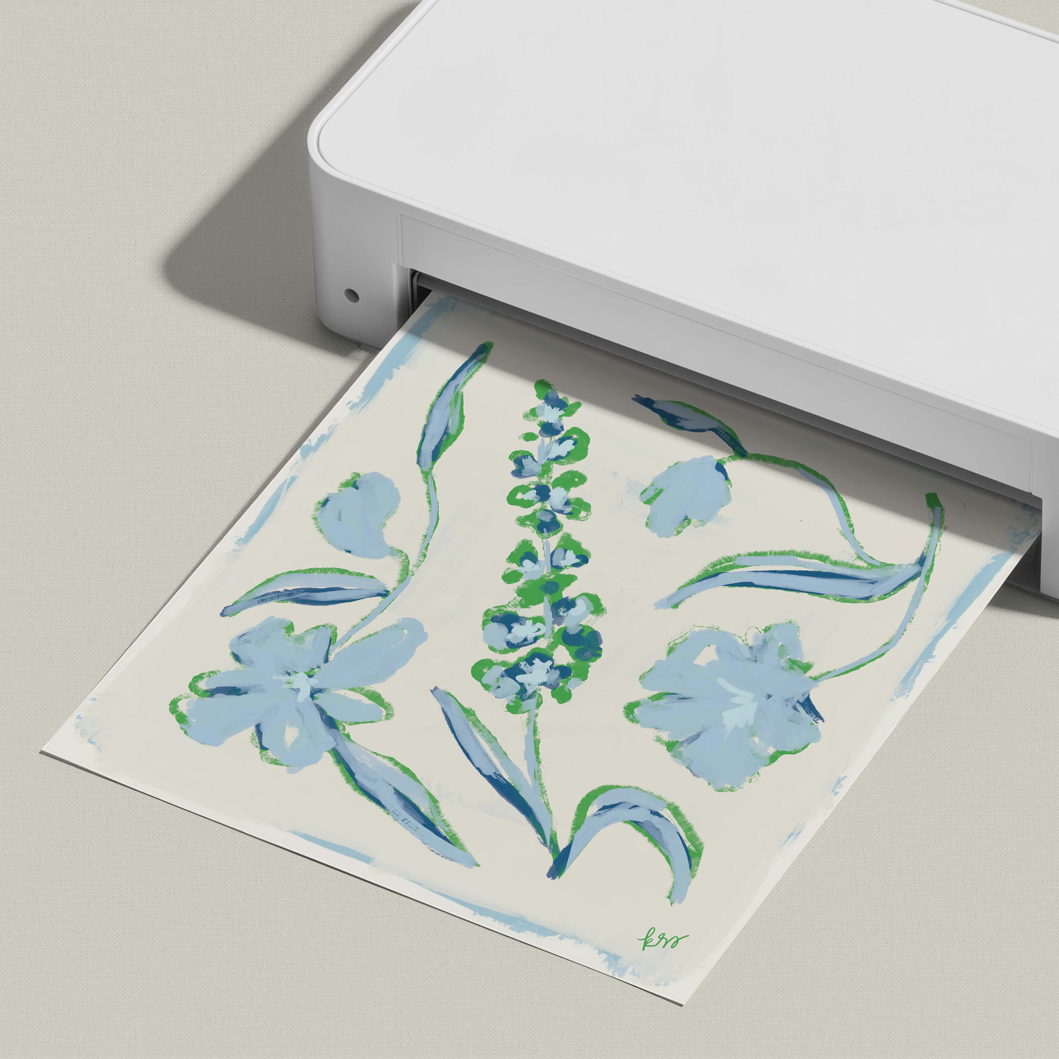 A white printer is printing a paper with a floral design featuring blue flowers and green leaves.