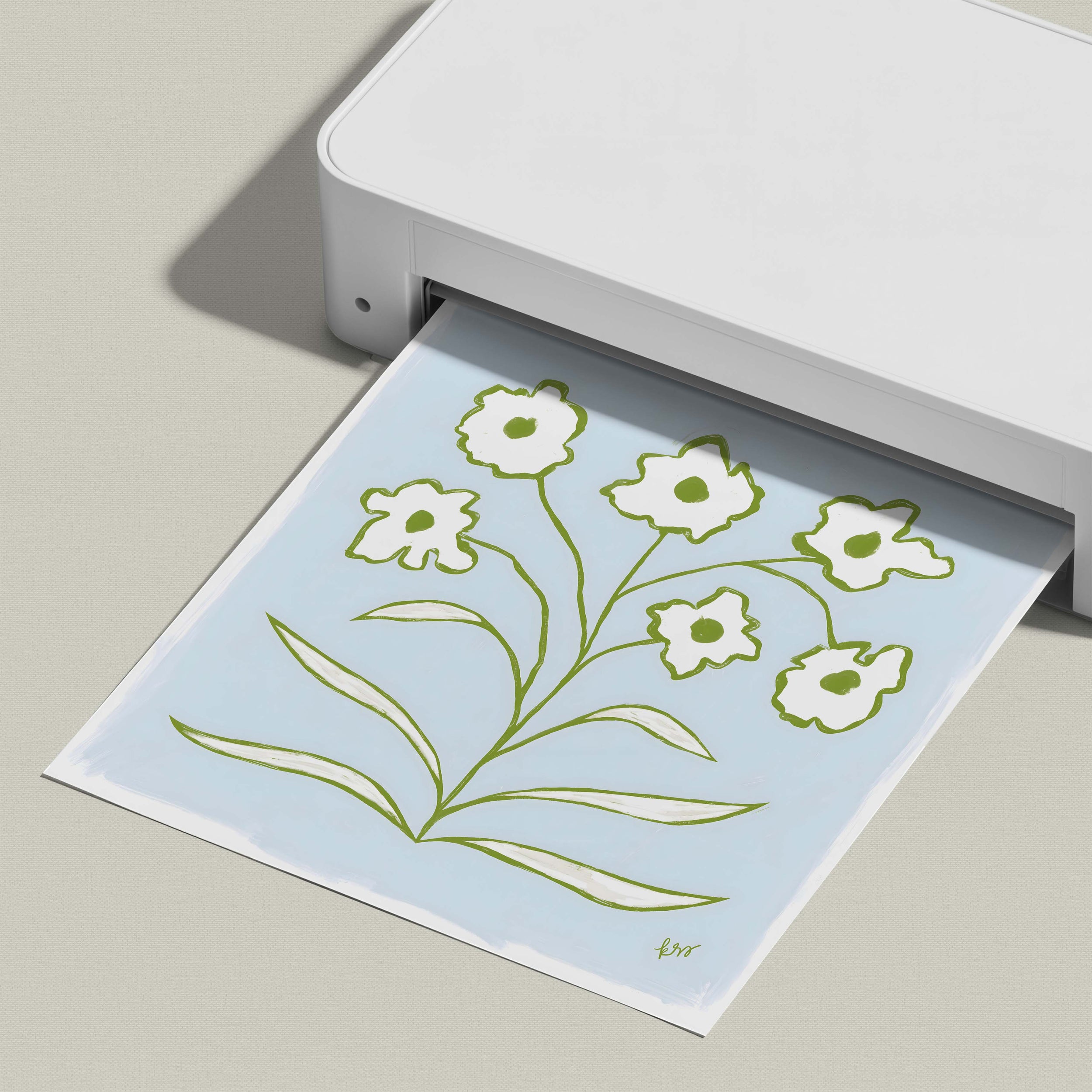 A white printer is printing a paper with a floral design on it.