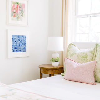 a cozy bedroom corner with a bed, a wooden nightstand, and a framed artwork on the wall.