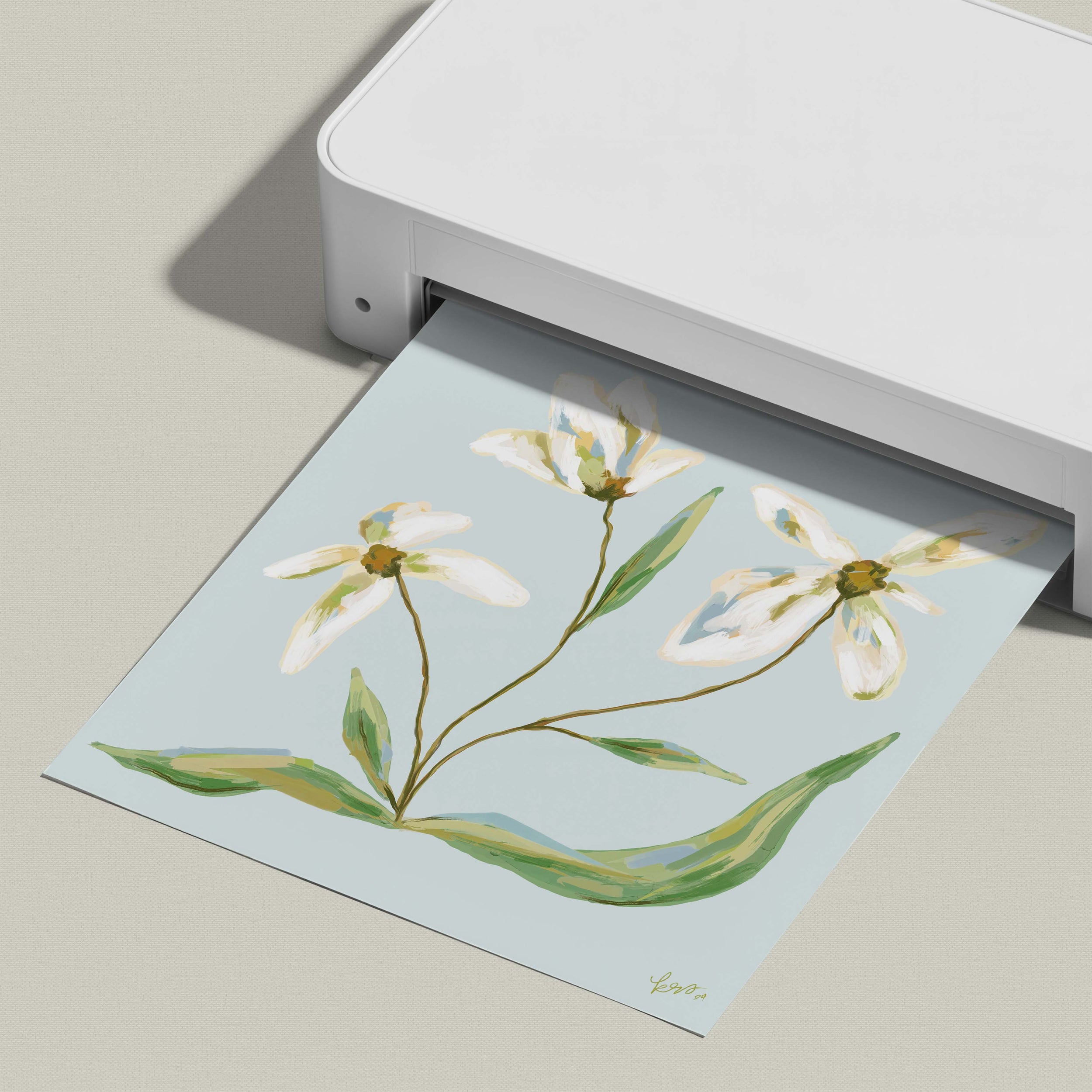 A white printer is printing a paper with a floral design featuring white flowers and green leaves.