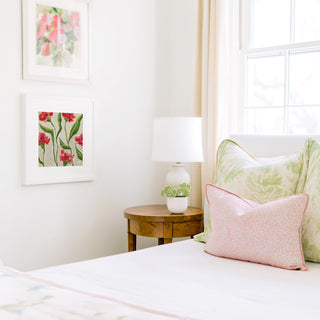 a cozy bedroom corner with a bed, a wooden nightstand, and a framed floral artwork on the wall.