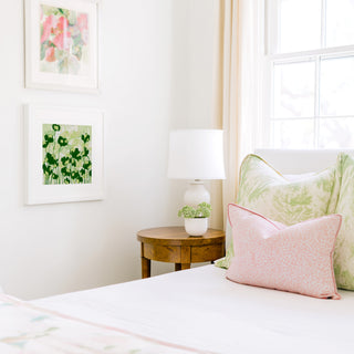 a cozy bedroom corner with a bed, a wooden nightstand, and a framed artwork on the wall.