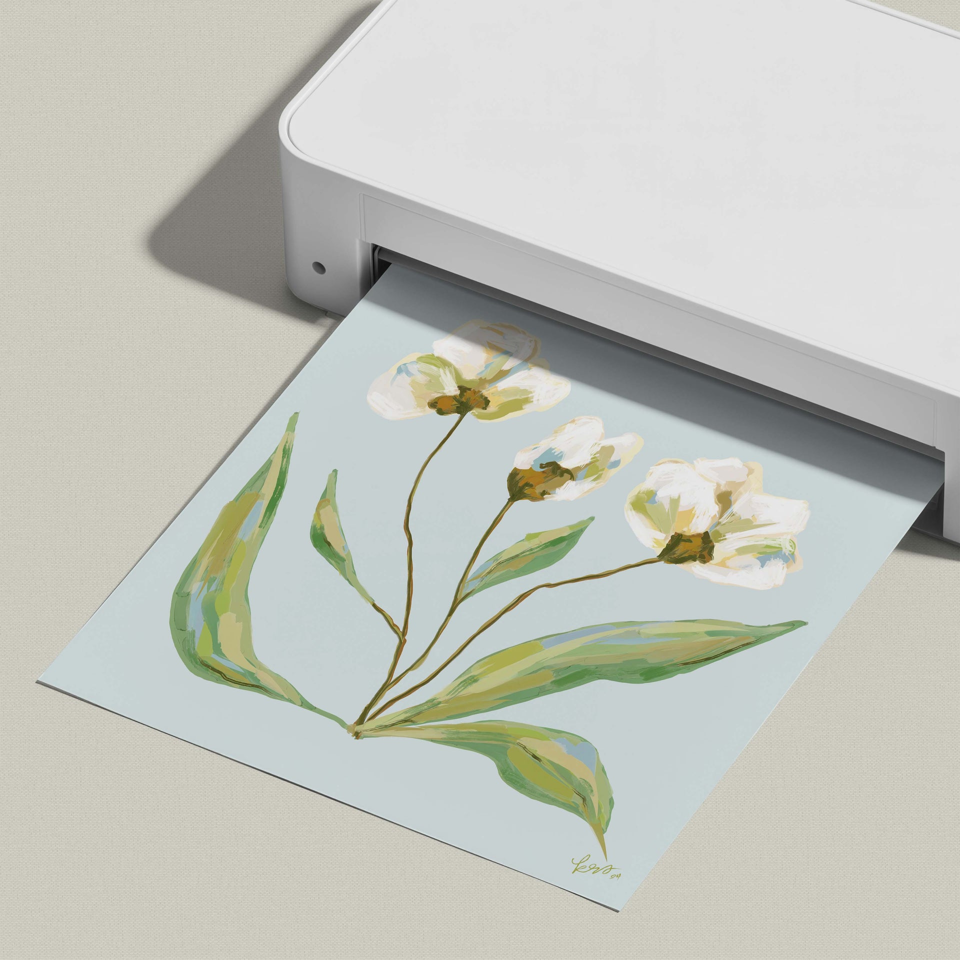A white printer is printing a paper with a floral design featuring white flowers and green leaves.