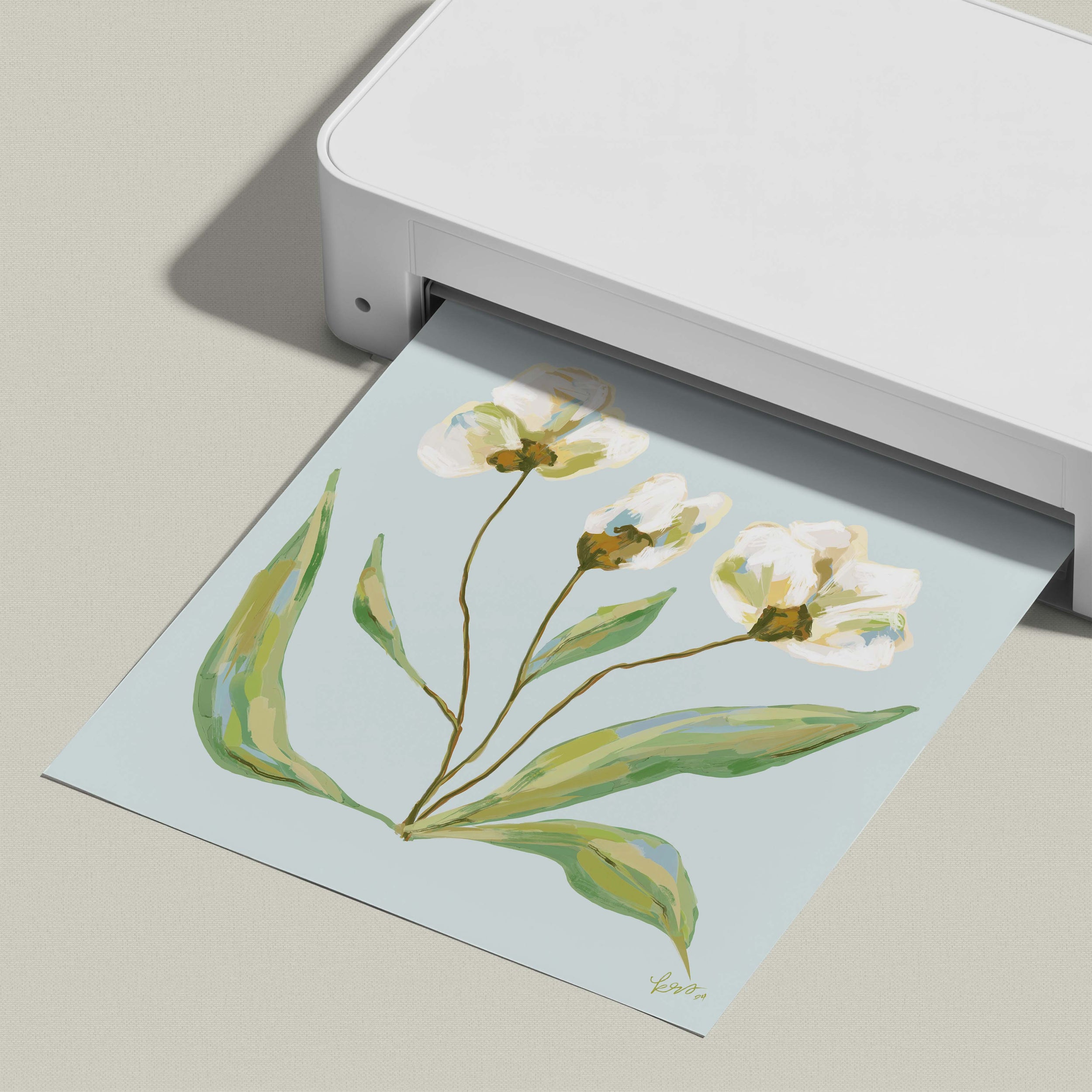 A white printer is printing a paper with a floral design featuring white flowers and green leaves.