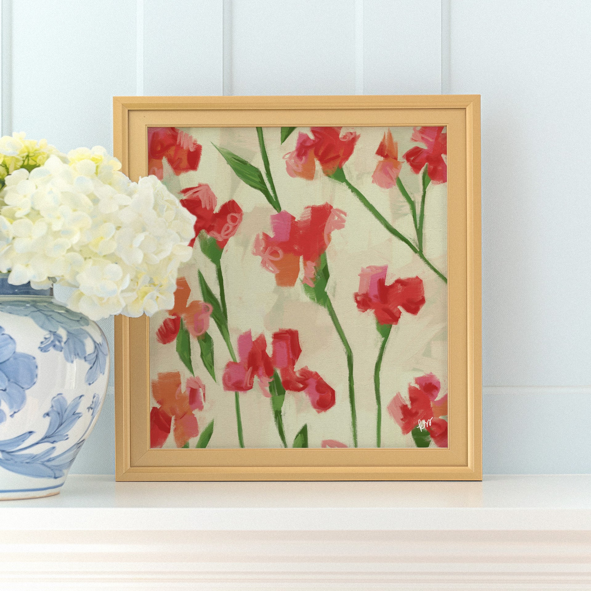 a framed painting of red flowers on a white background, placed on a shelf next to a blue and white vase filled with white hydrangeas.