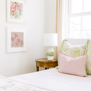 a cozy bedroom corner with a bed, a wooden nightstand, and a framed artwork on the wall.