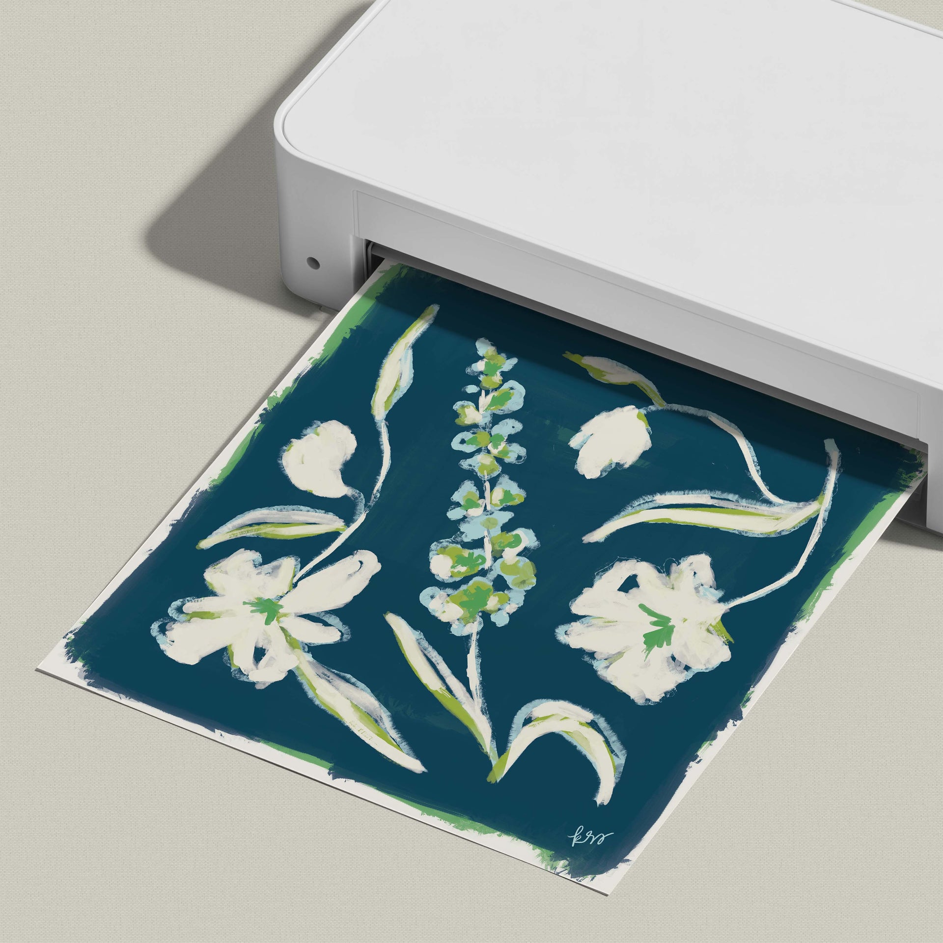 A white printer is displaying a printed image of a floral design on a blue background.