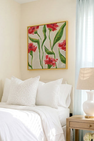 a cozy bedroom with a bed, white bedding, and a framed floral artwork hanging on the wall above it.