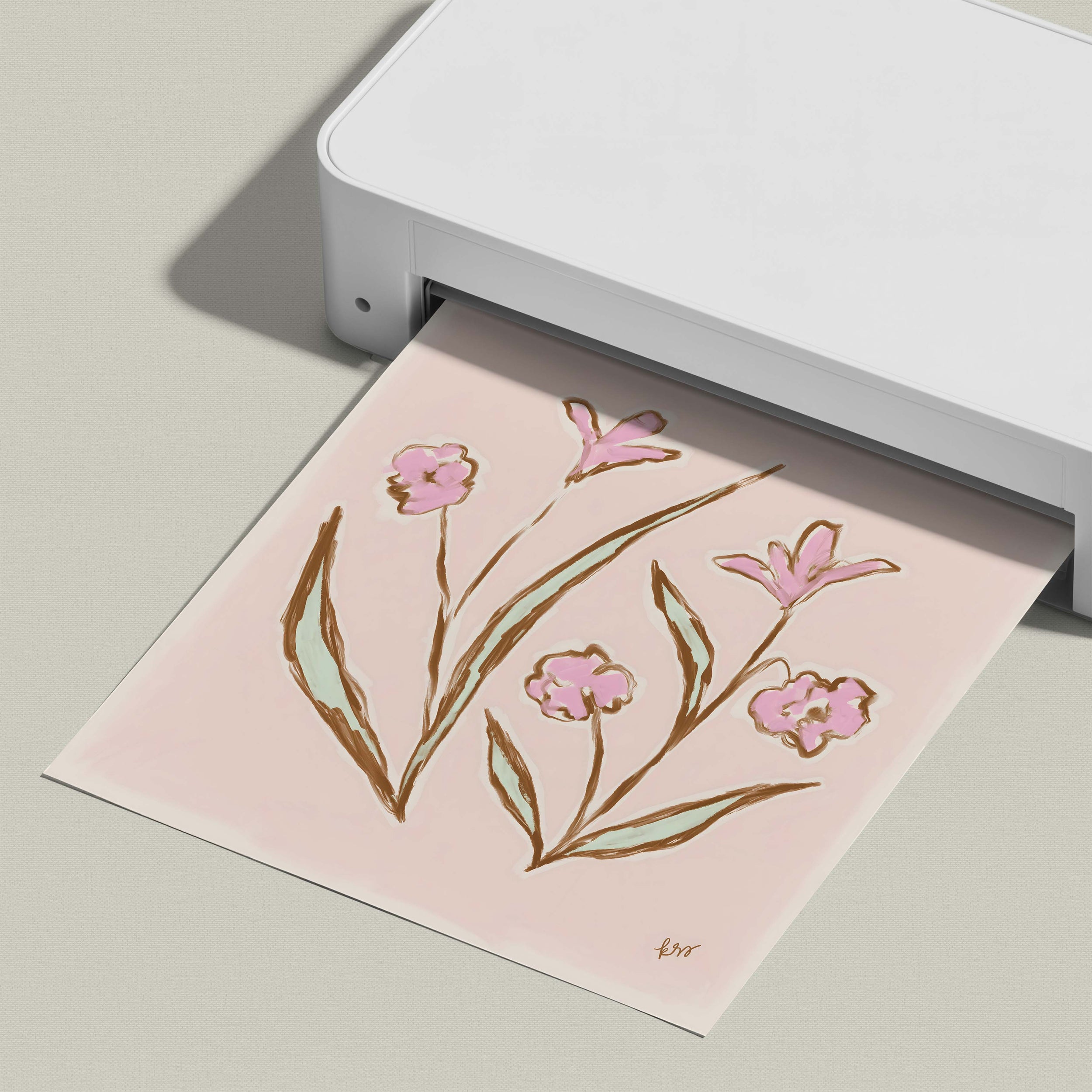 A white printer is printing a pink floral design on a piece of paper.