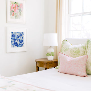 a cozy bedroom corner with a bed, a wooden nightstand, and a framed artwork on the wall.
