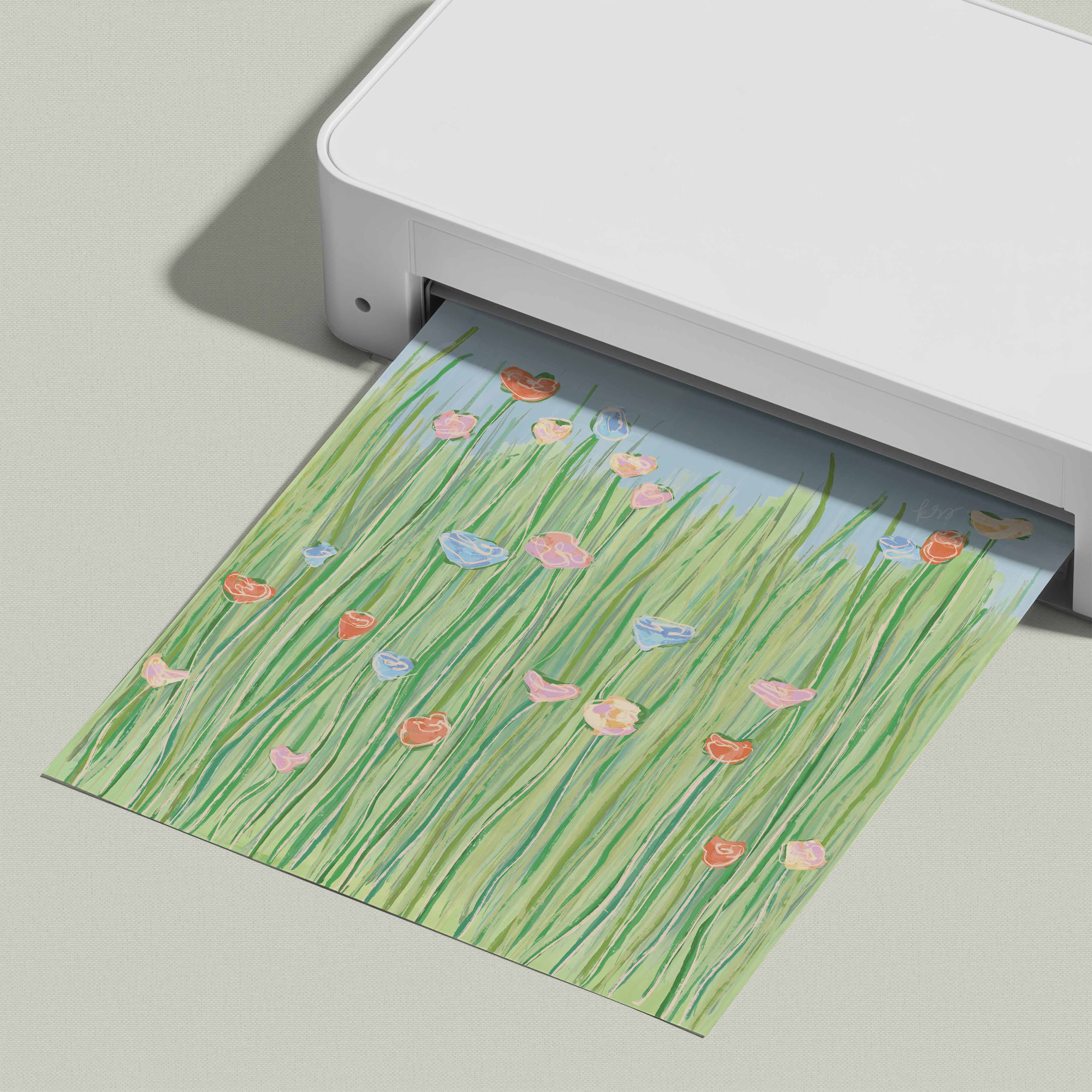 A white printer is shown with a printed paper featuring a colorful illustration of flowers and grass.
