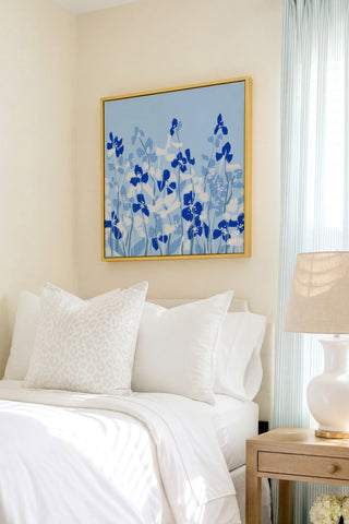 a serene bedroom scene with a bed adorned with white linens and a framed floral artwork hanging above it.