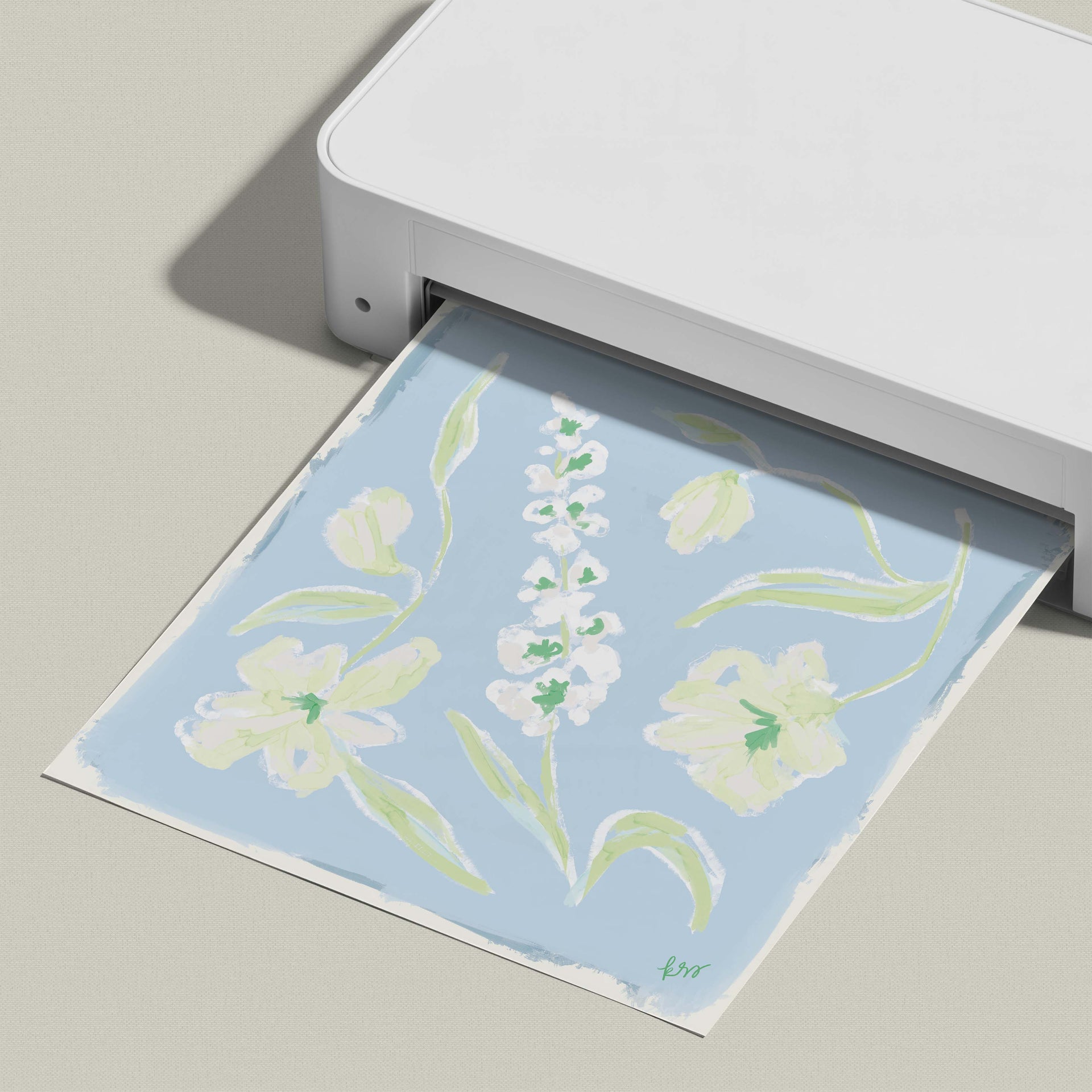 A white printer is printing a paper with a blue floral design on it.