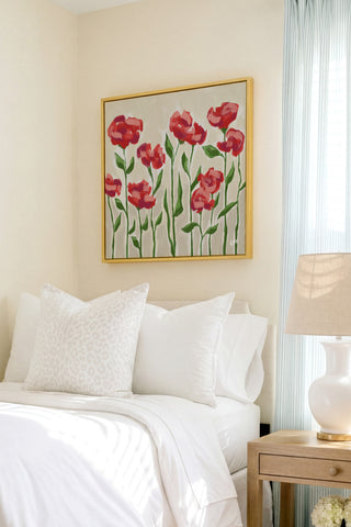 a bedroom with a bed, a nightstand, and a framed artwork of red flowers on the wall.