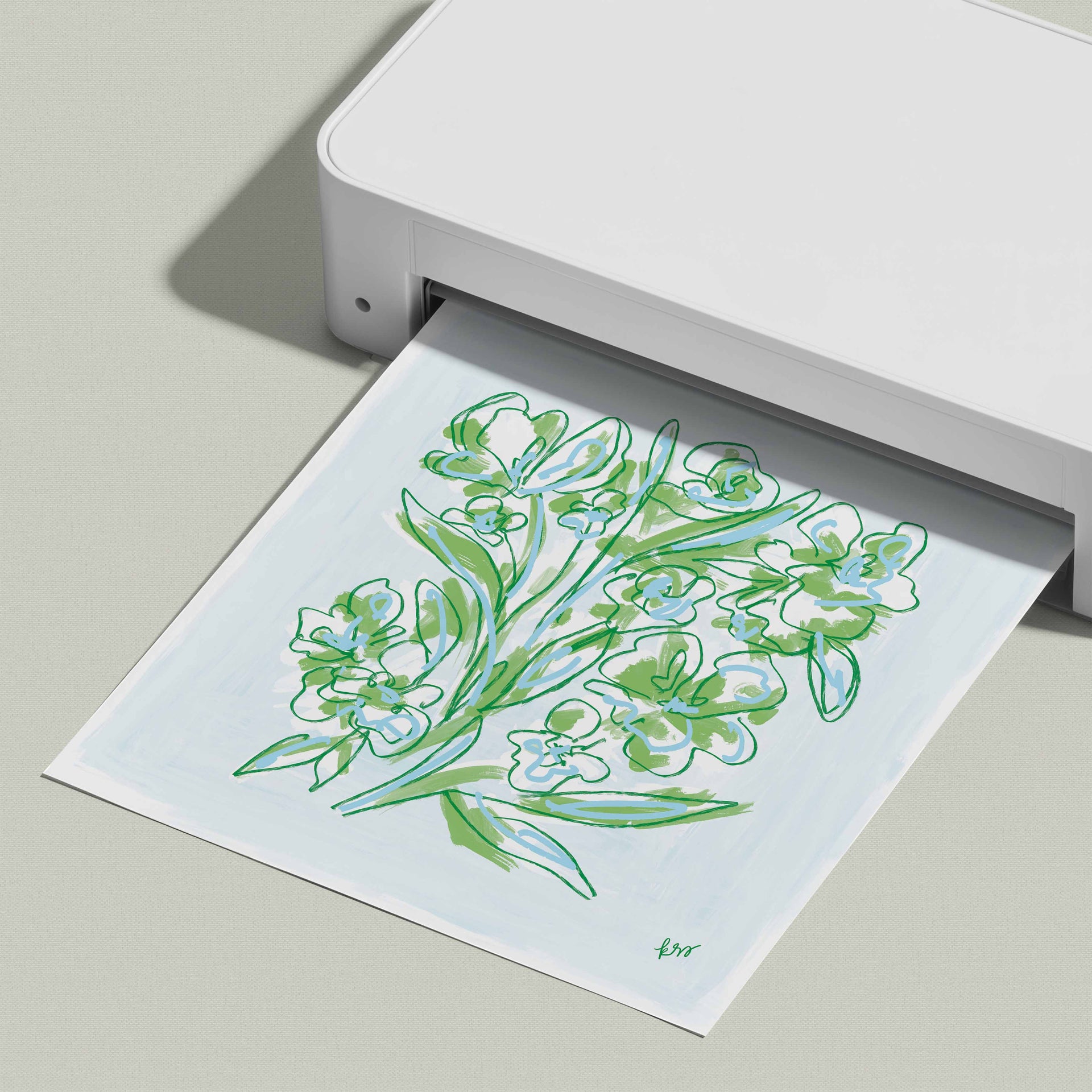 A white printer is printing a paper with a green and white floral design.