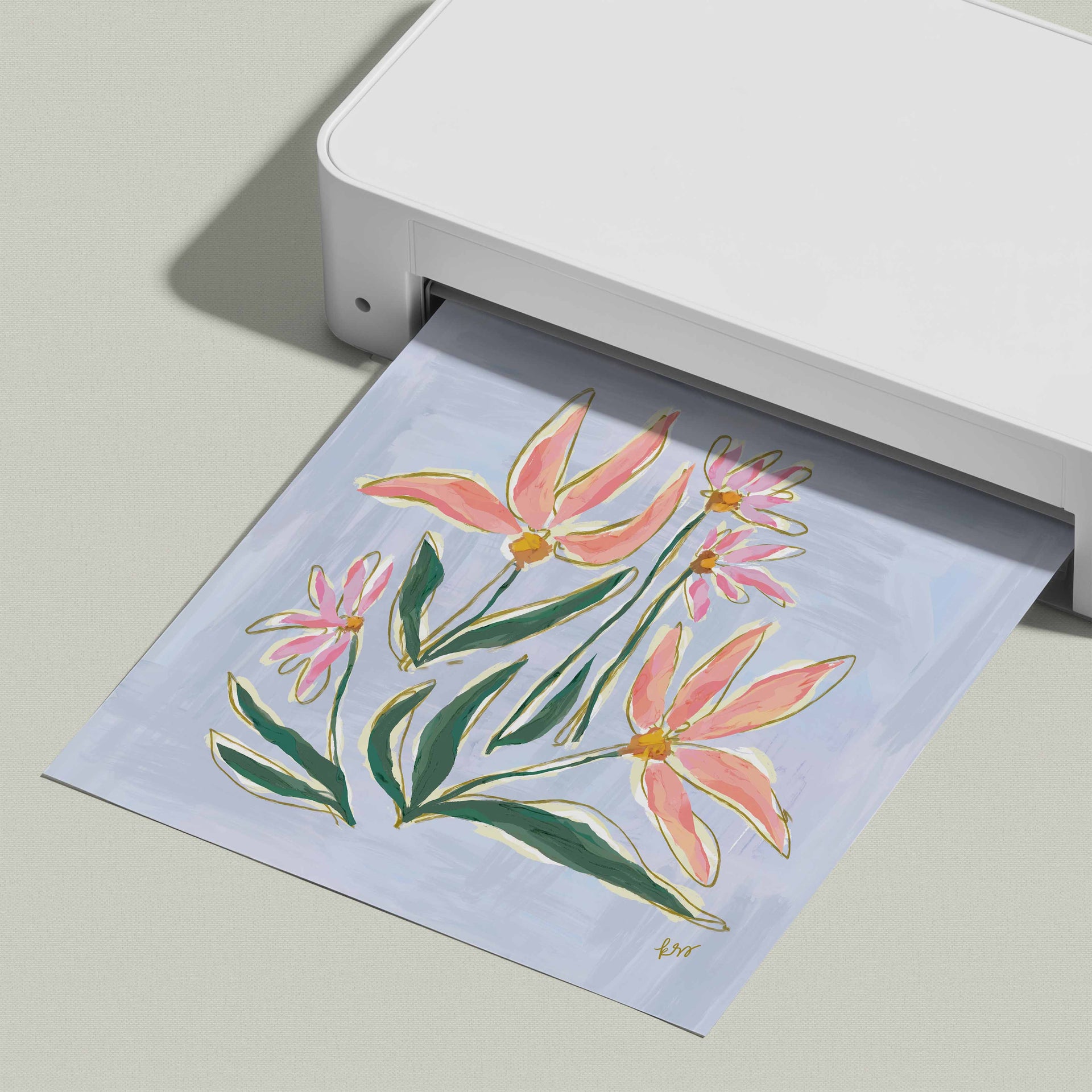 A white printer is displaying a printed image of a floral design on a light blue background.