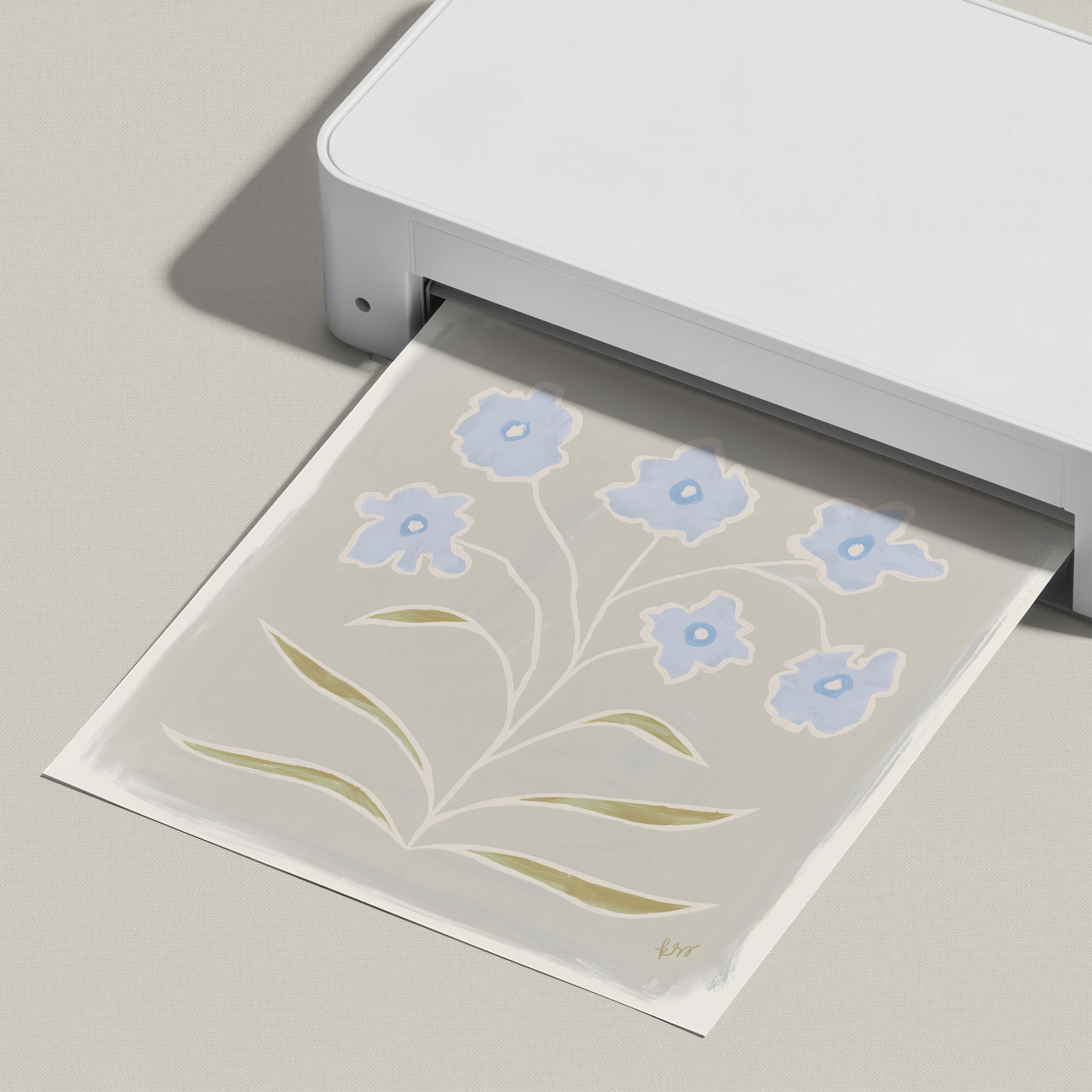 A white printer is shown in the image, with a printed paper displaying a floral design featuring blue flowers and green leaves.