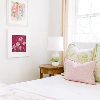 a cozy bedroom corner with a bed, a wooden nightstand, and a framed artwork on the wall.