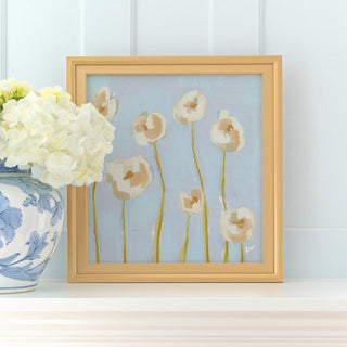 a framed painting of white flowers with yellow stems, placed on a white shelf next to a blue and white vase with white flowers.