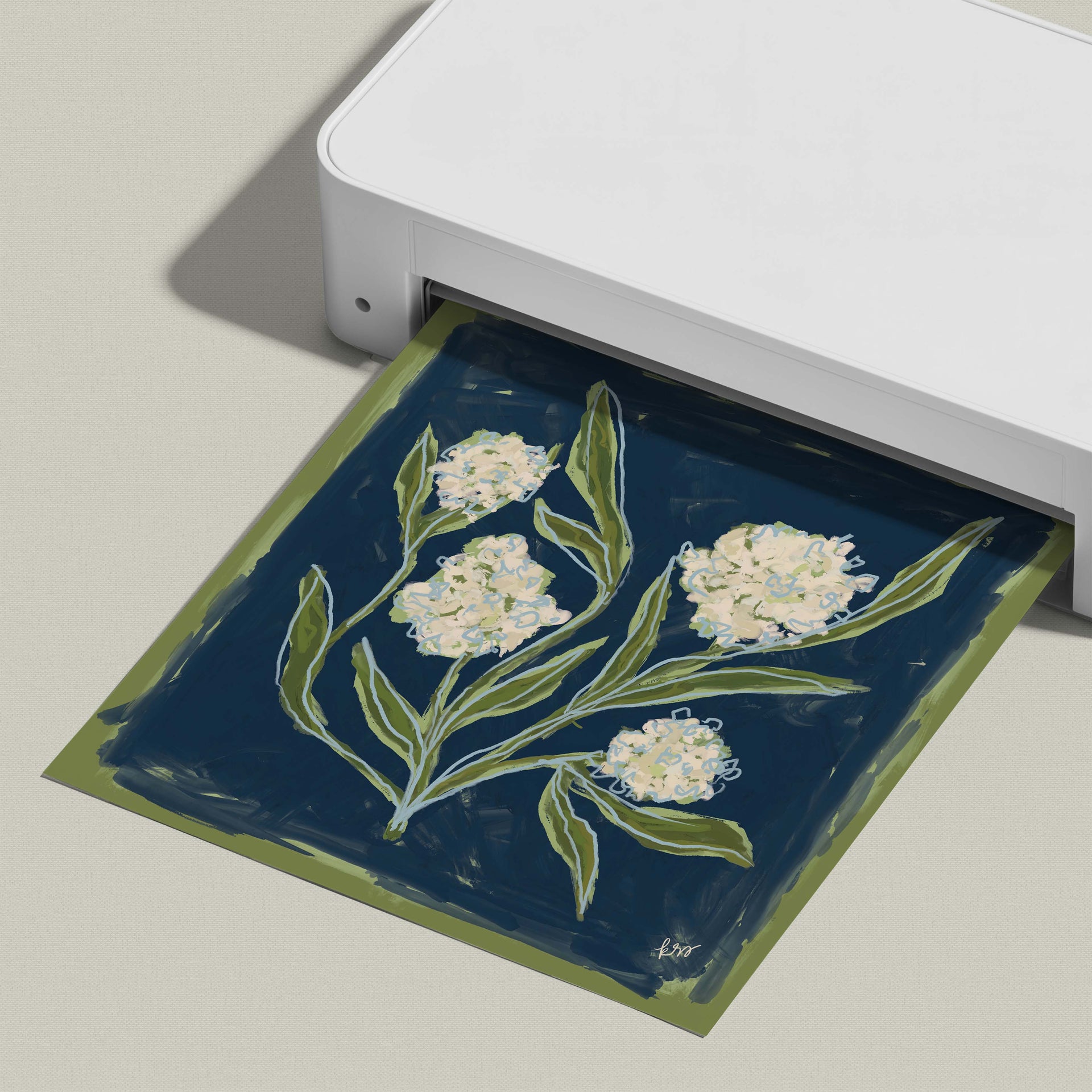 A white printer is shown with a printed paper featuring a floral design in shades of blue and green.