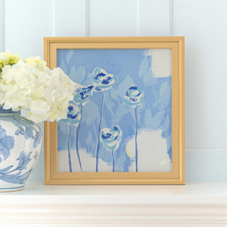 a framed painting of blue flowers on a white shelf, accompanied by a vase of white hydrangeas.