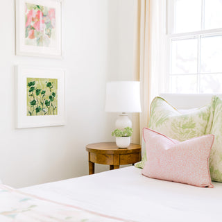 a cozy bedroom corner with a bed, a wooden nightstand, and a framed artwork on the wall.