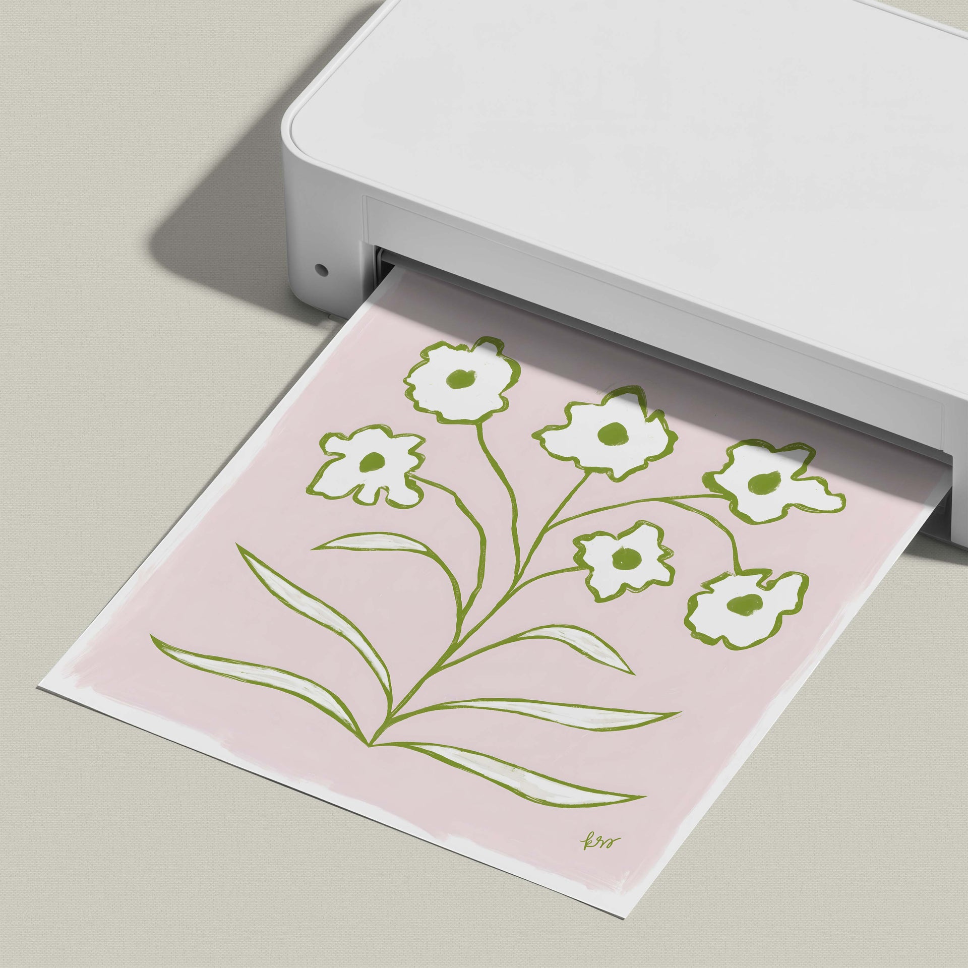 A white printer is printing a pink paper with a green floral design on it.