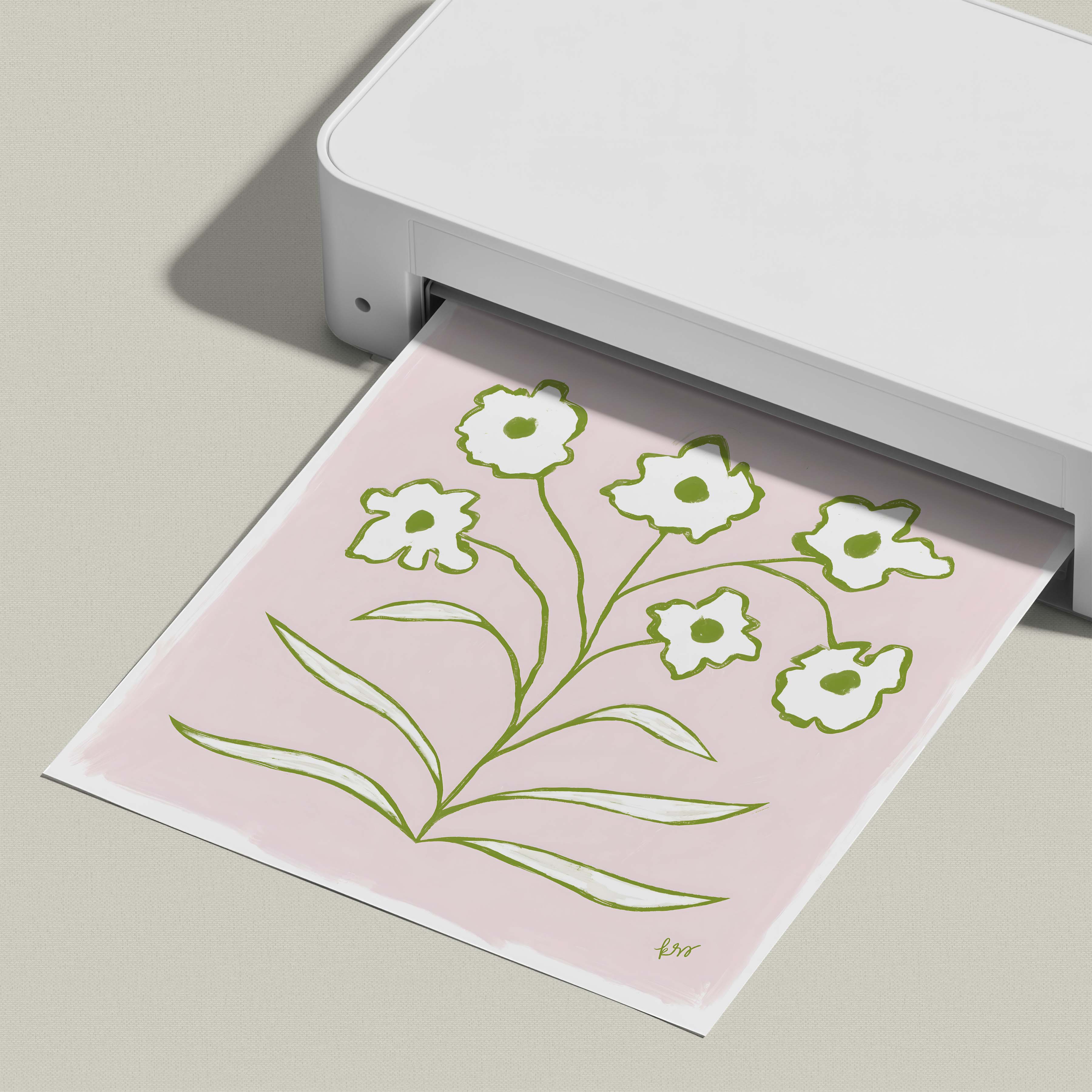 A white printer is printing a pink paper with a green floral design on it.