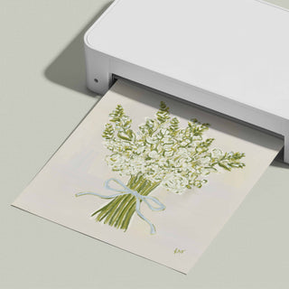 A white printer is printing a picture of a bouquet of white flowers with a blue ribbon.