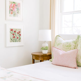 a cozy bedroom corner with a bed, a wooden nightstand, and a framed artwork on the wall.