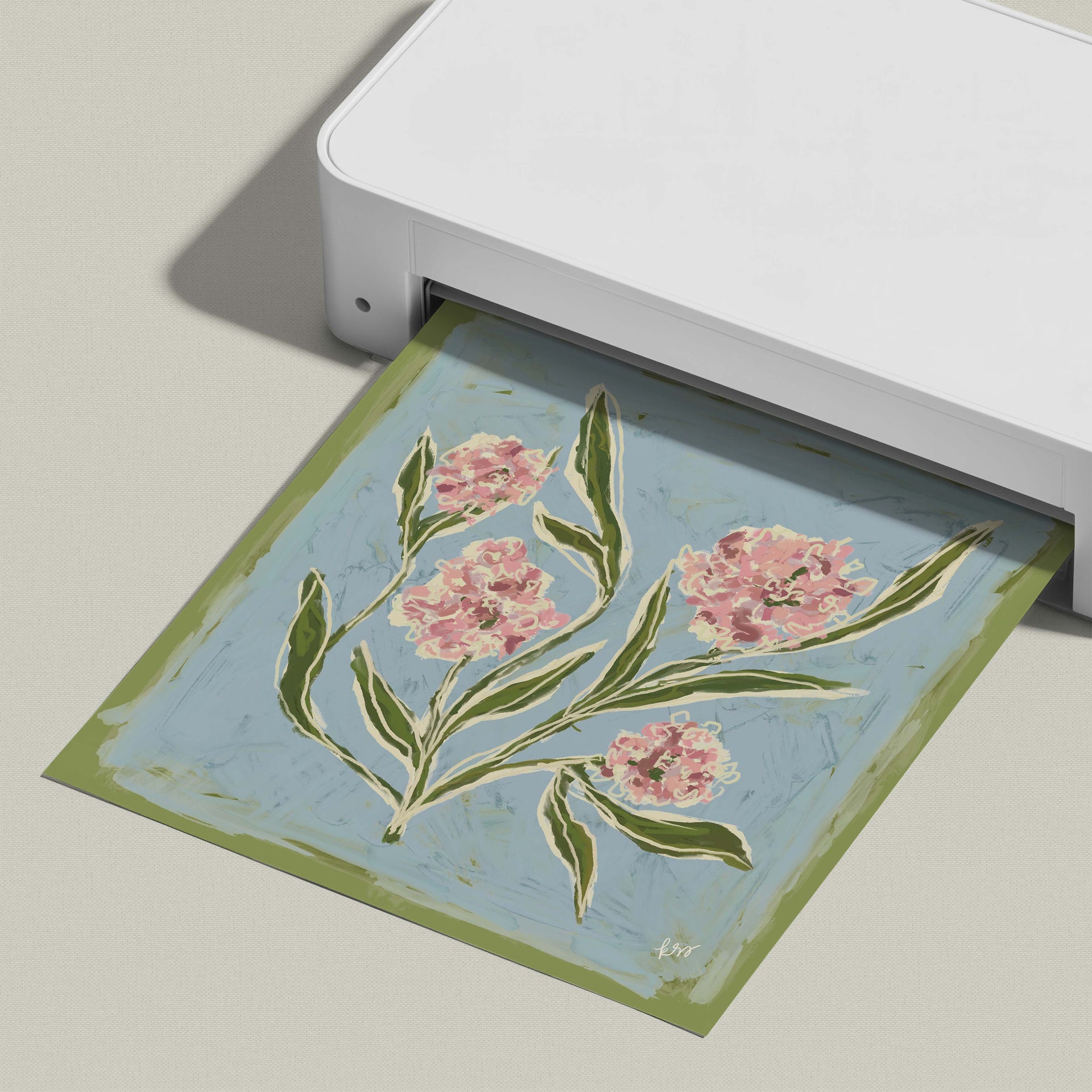 A white printer is displaying a printed image of a floral design on a blue background.