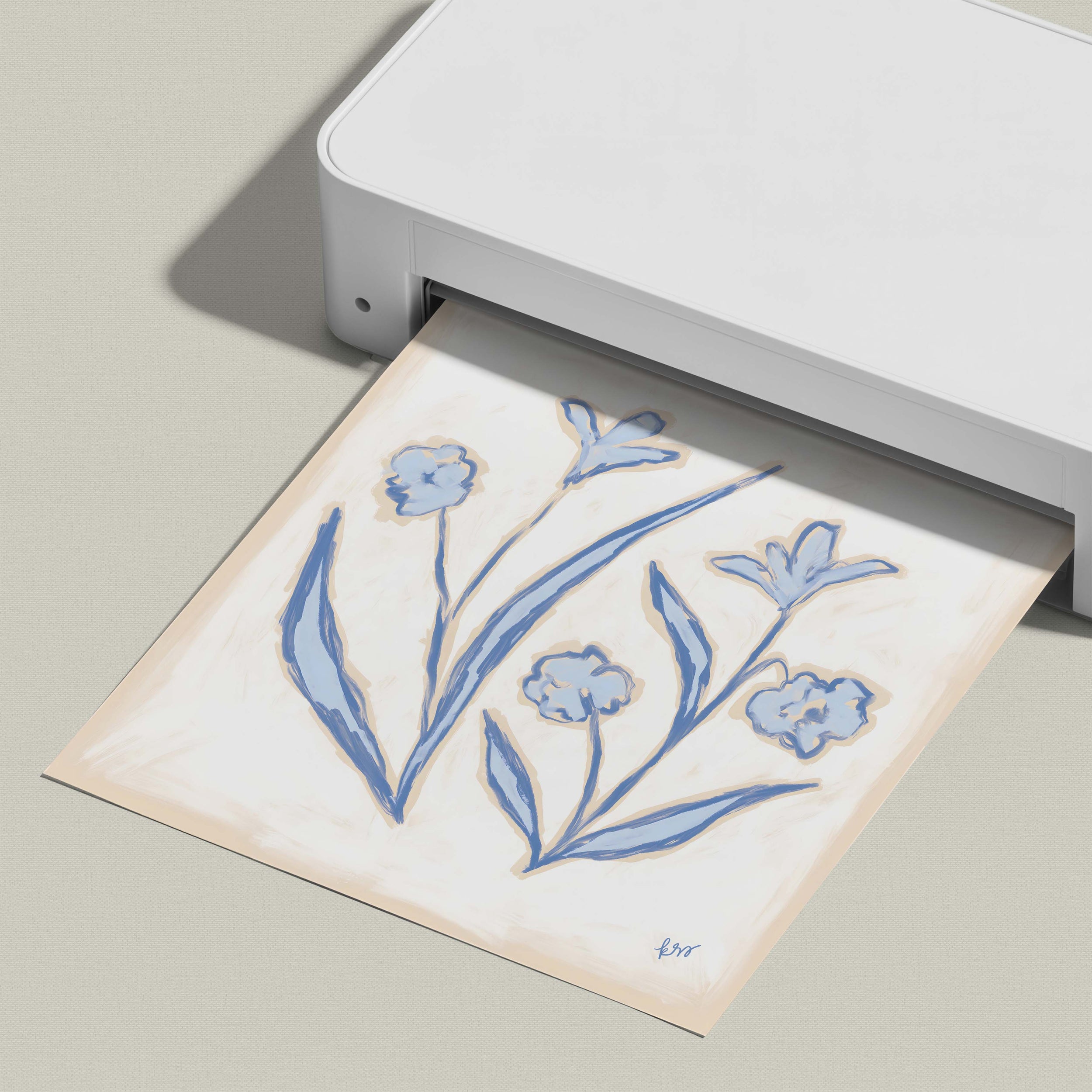 A white printer is printing a paper with a blue floral design on it.