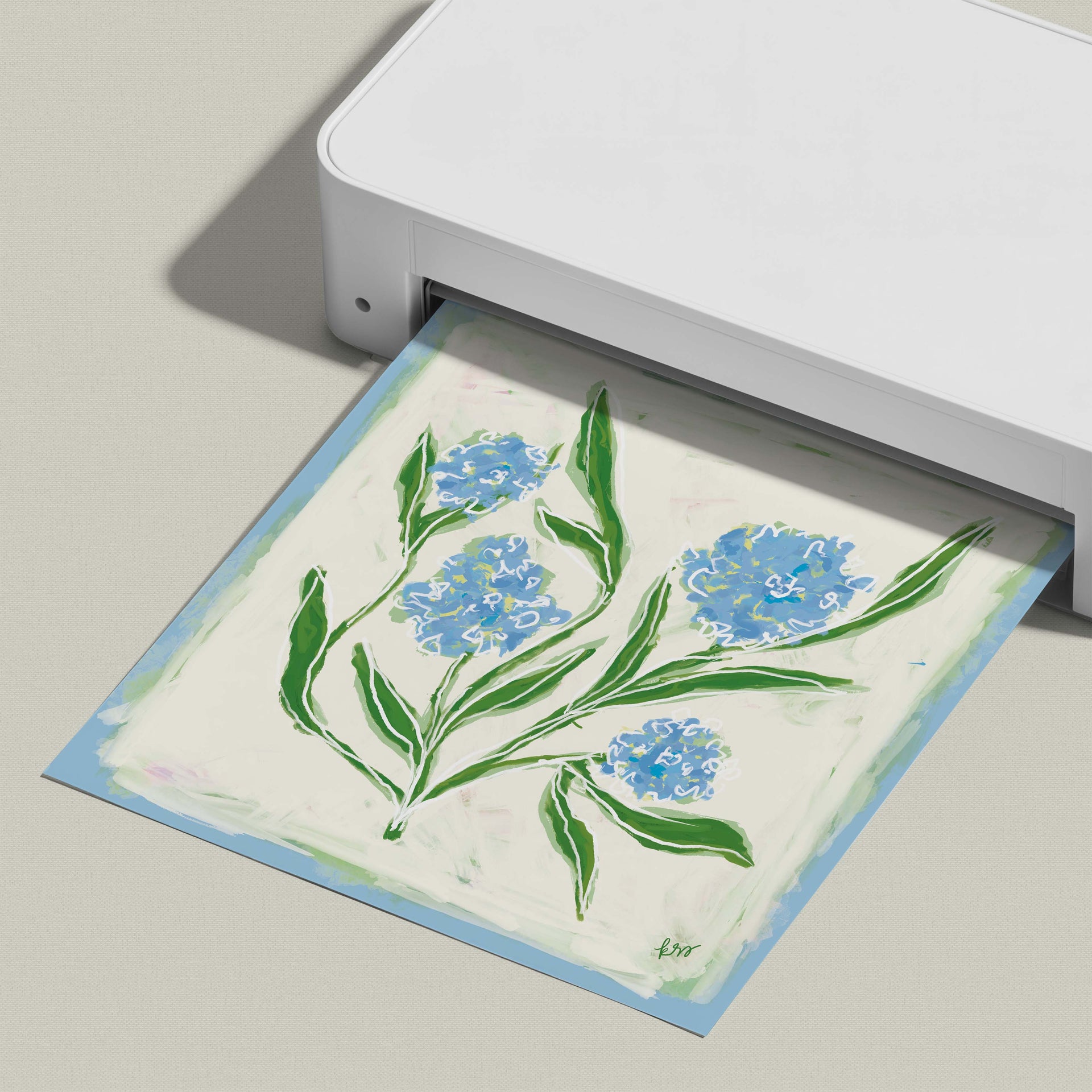 A white printer is printing a paper with a blue and green floral design.