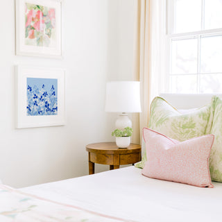 a cozy bedroom corner with a bed, a wooden nightstand, and a framed artwork on the wall.