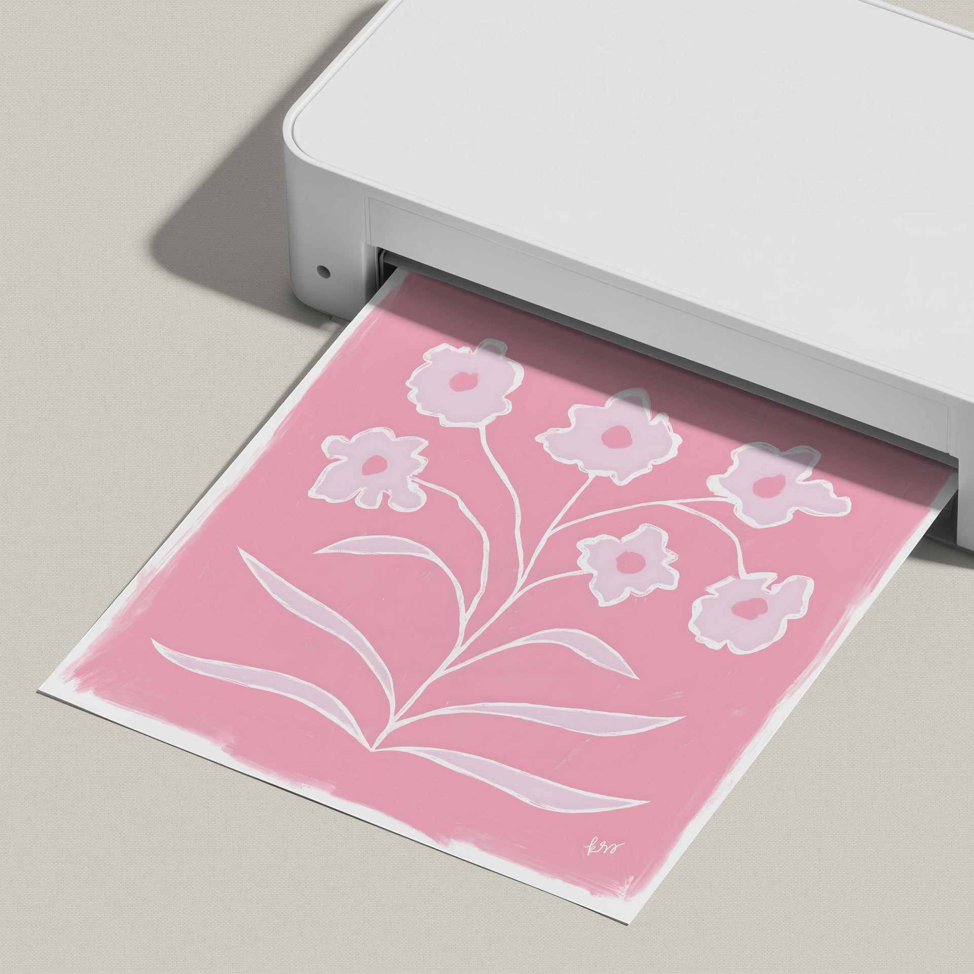 A white printer is printing a pink floral design on a piece of paper.