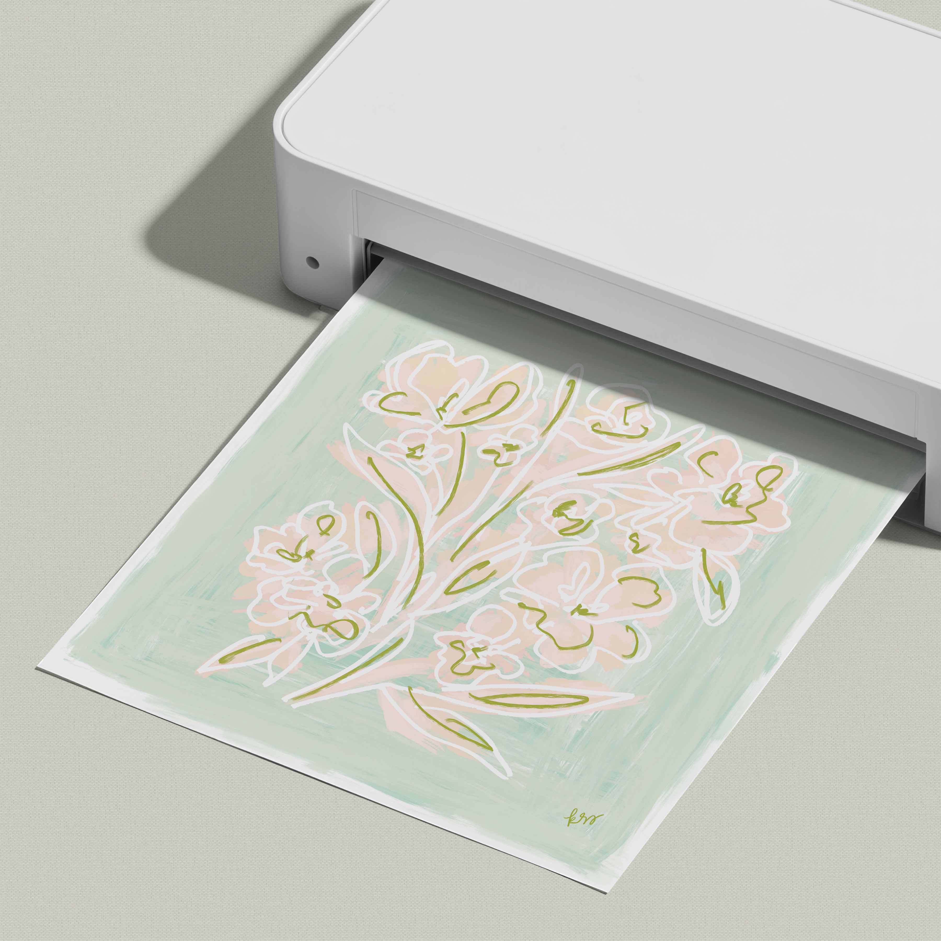 A white printer is displaying a printed image of a floral design on a light green background.