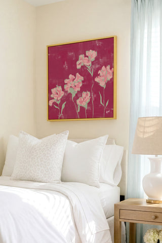 a bedroom with a bed, a nightstand, and a framed artwork featuring pink flowers on the wall.