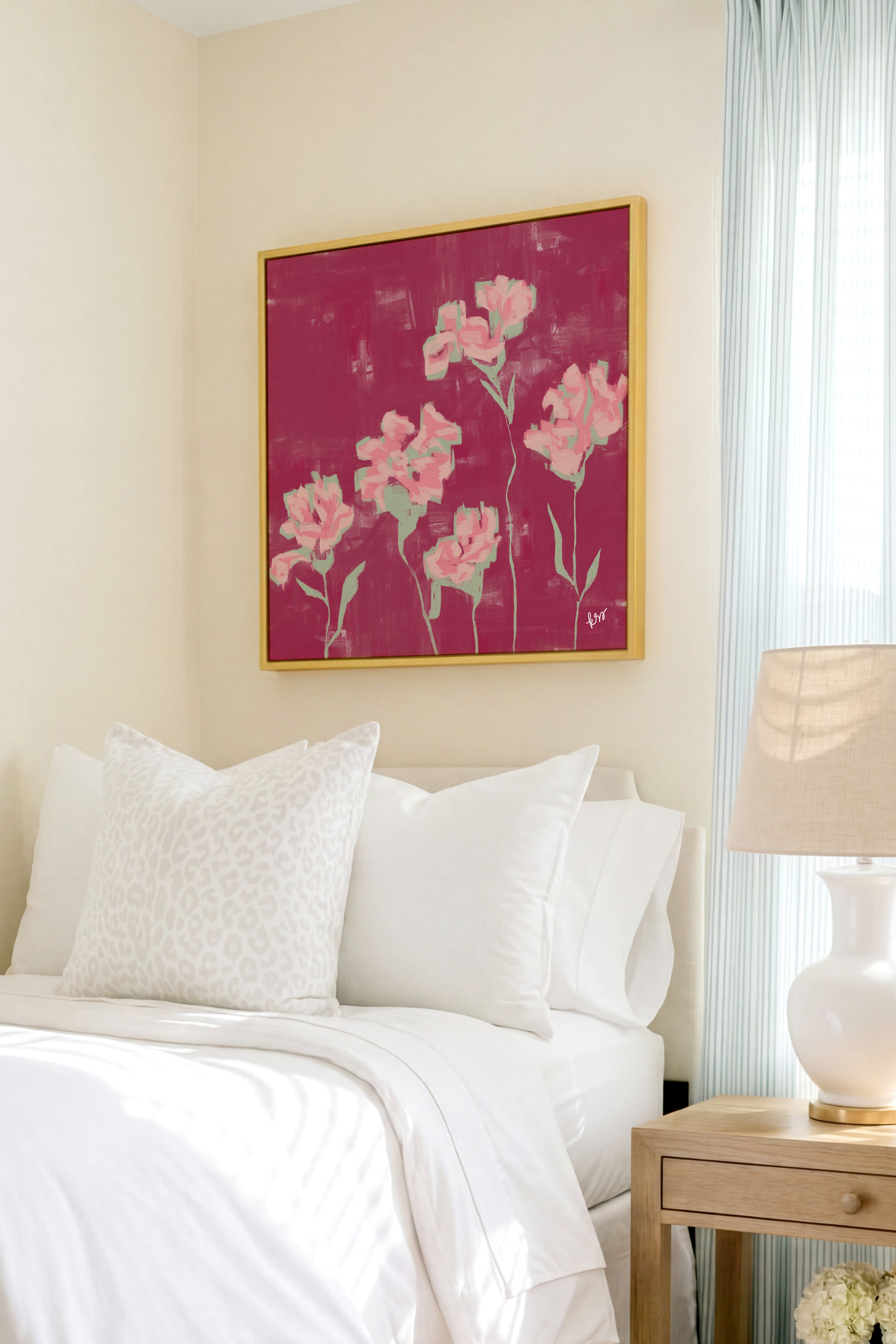 a bedroom with a bed, a nightstand, and a framed artwork featuring pink flowers on the wall.
