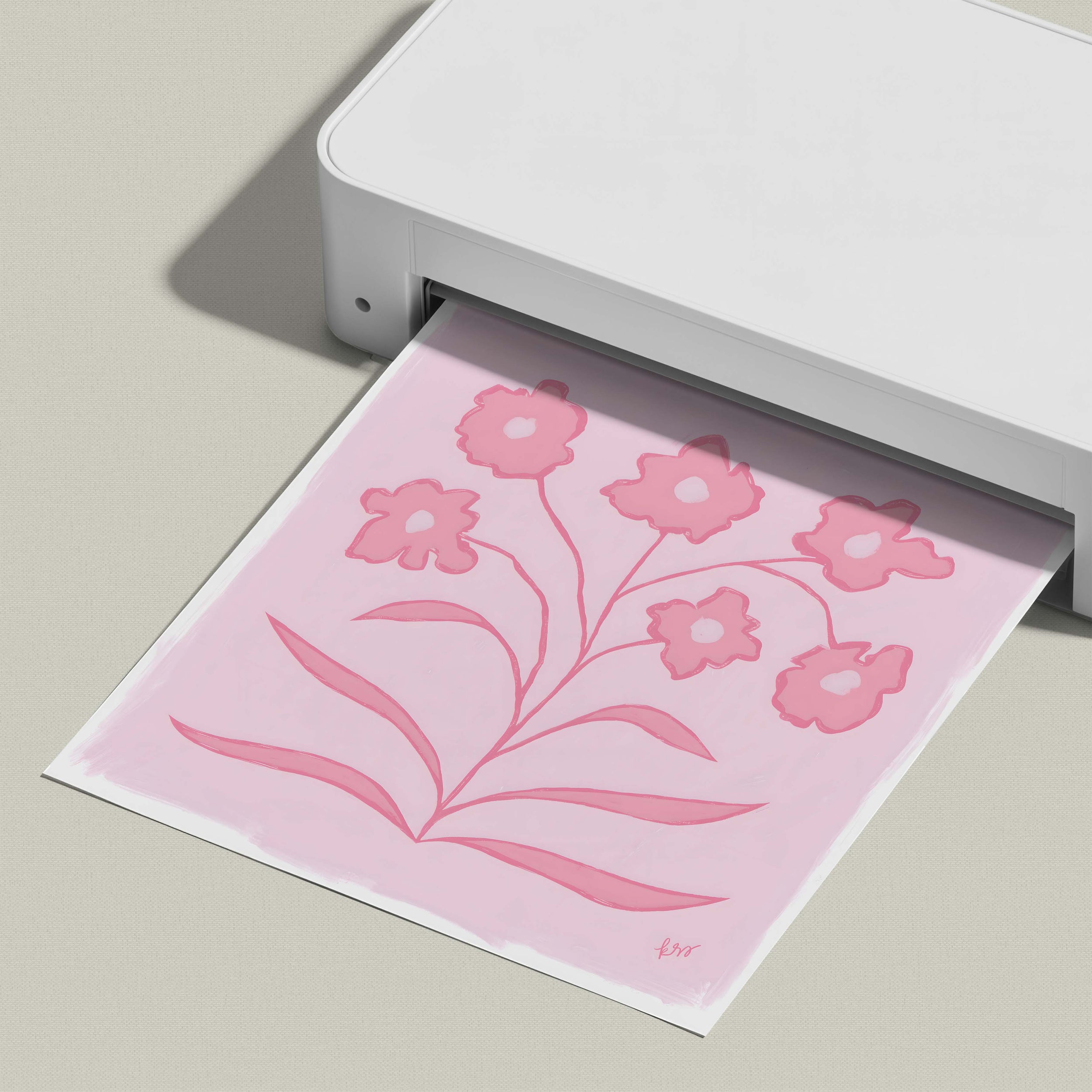 A white printer is printing a pink floral design on a piece of paper.