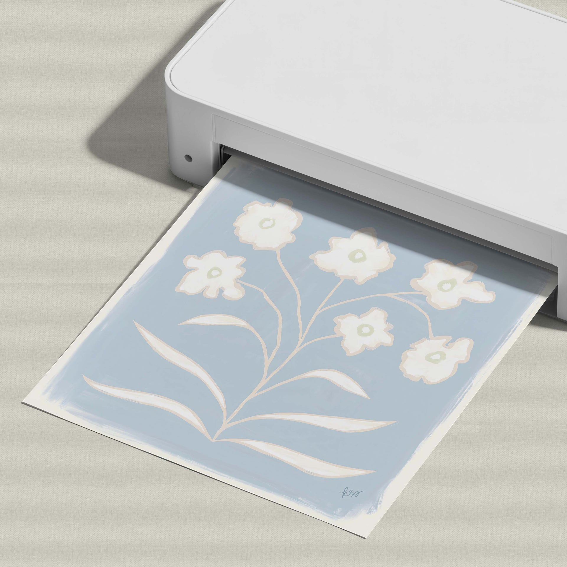 A white printer is printing a blue and white floral design on a piece of paper.