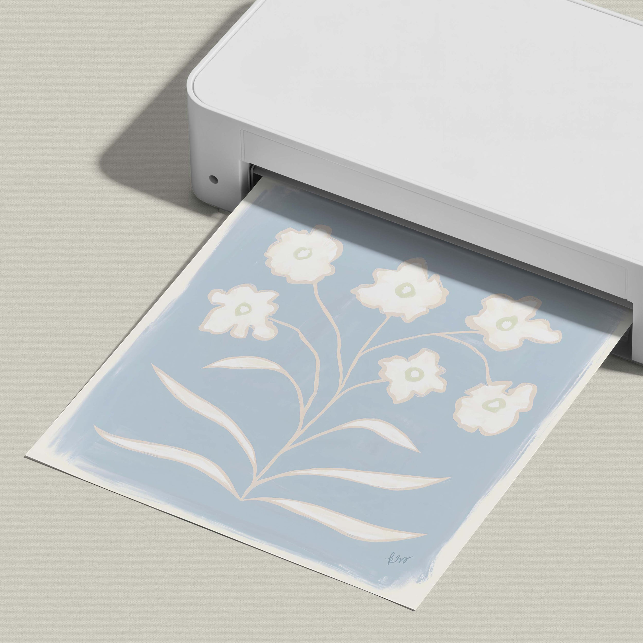 A white printer is printing a blue and white floral design on a piece of paper.