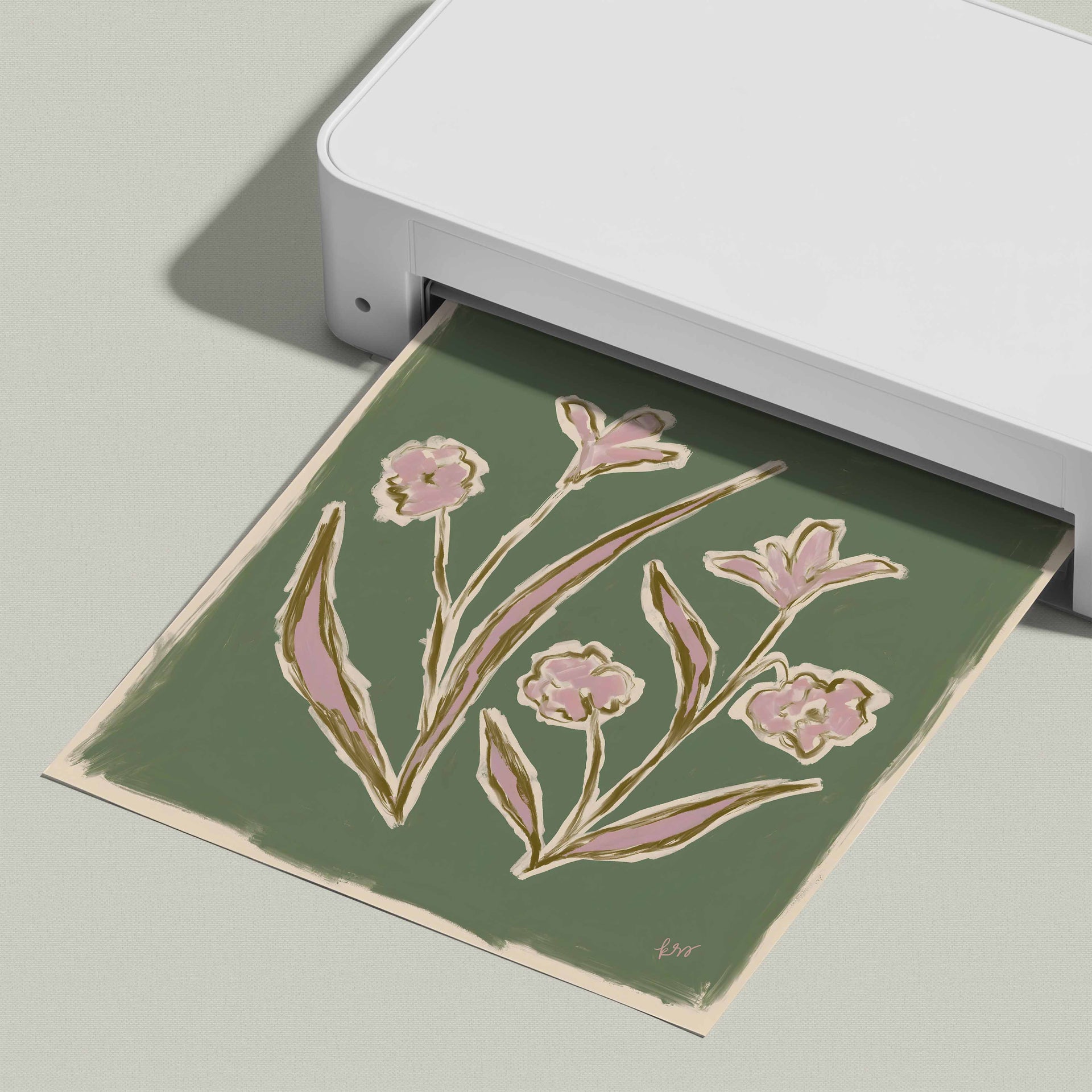 A white printer is displaying a green paper with an illustration of pink flowers.
